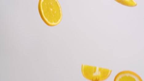 Bright-orange-citrus-orange-slices-raining-on-white-backdrop-in-slow-motion