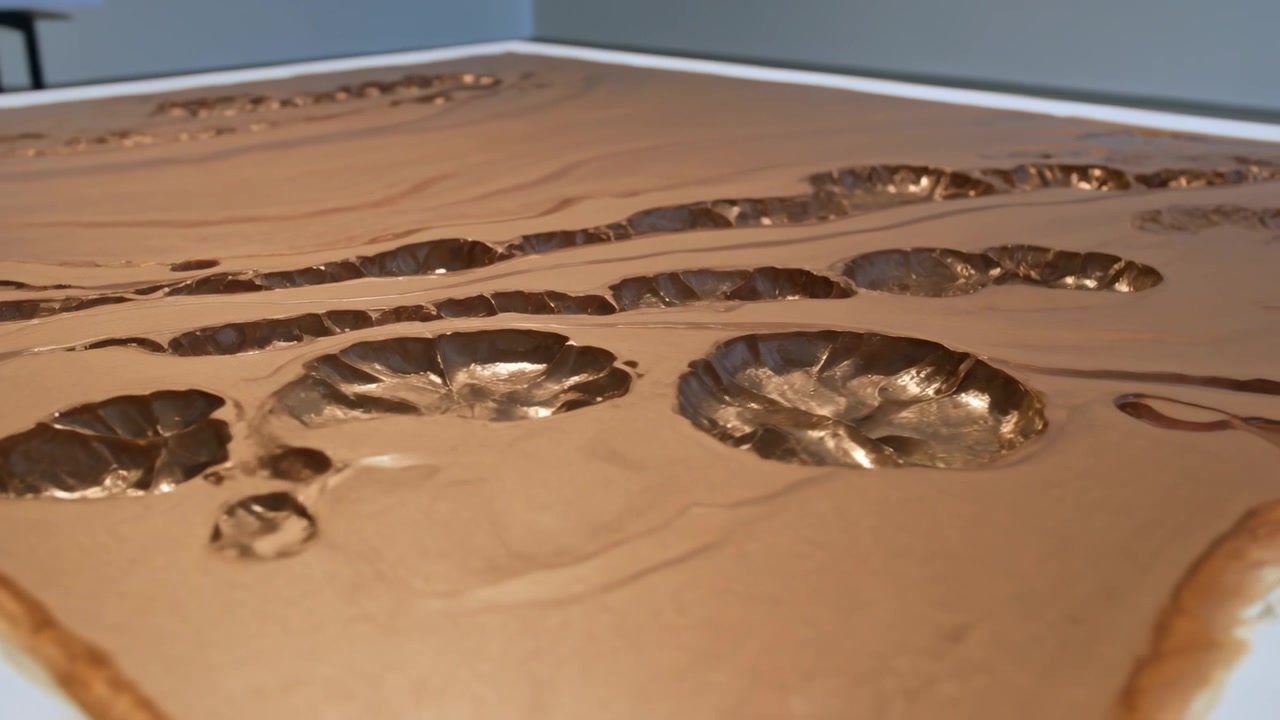 Rivestimento marrone lucido che si sviluppa formando giunture e crateri a forma di coppa mentre si raffredda su un vassoio bianco.