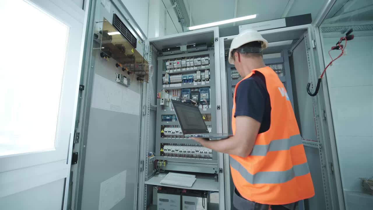 el ingeniero eléctrico que trabaja comprueba la tensión de corriente eléctrica y la sobrecarga en la parte delantera del gabinete del centro de carga o de la unidad de consumo para el mantenimiento en la sala principal del sistema de distribución de energía.