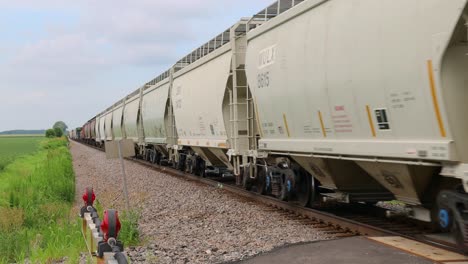 vagones de tren blancos acercándose a un cruce de ferrocarril en una zona rural