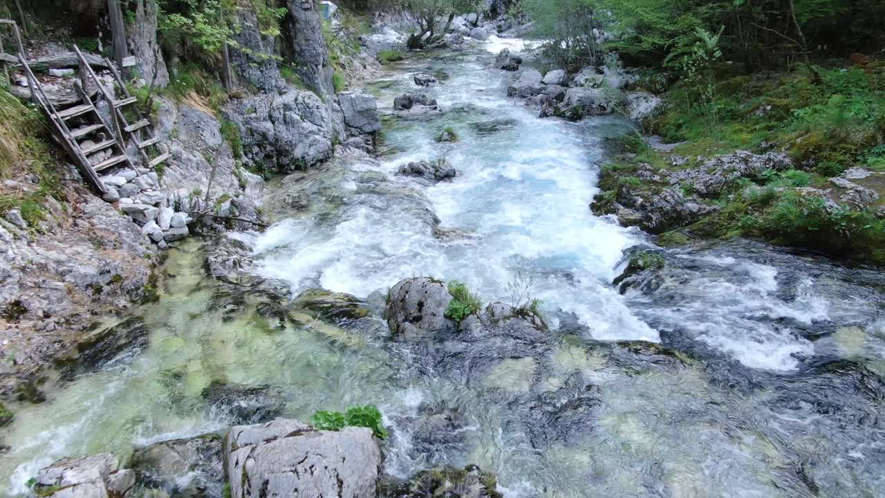 Drone view in Albania in the alps flying on top of a rapids river surrounded by green and rocky mountain in Theth