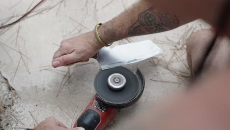 person sharpening a knife with an angle grinder