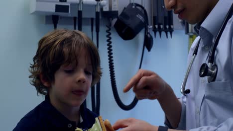 side view of young asian male doctor showing ear model to caucasian boy patient in clinic 4k