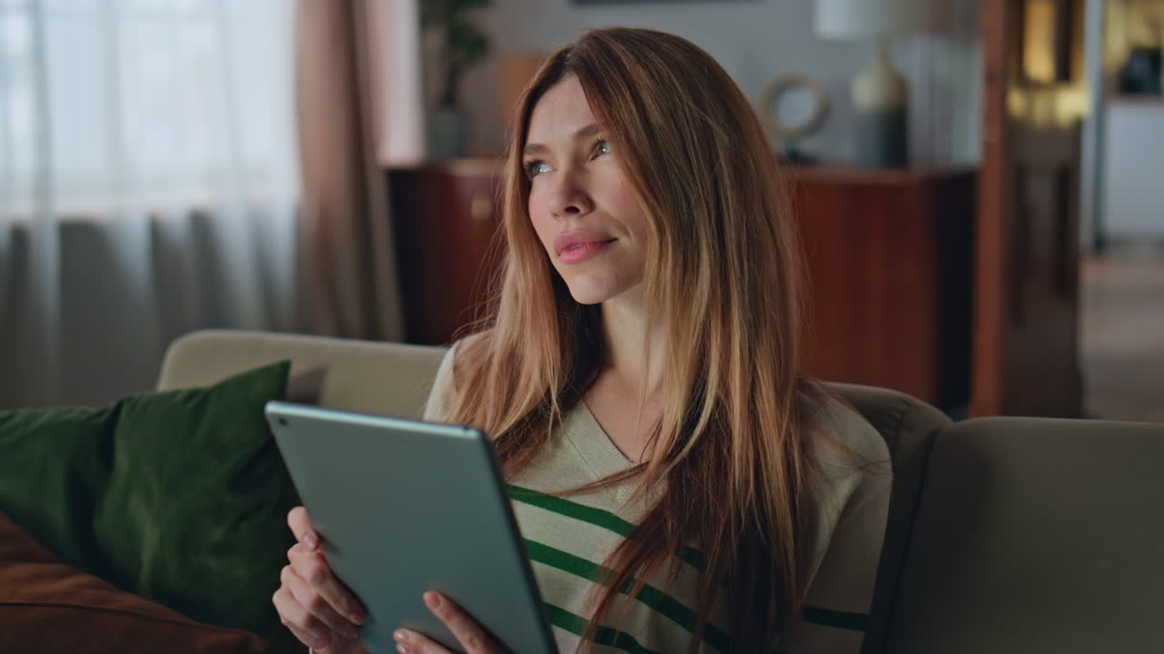 Online worker thinking task holding tablet at home close up. Woman choosing