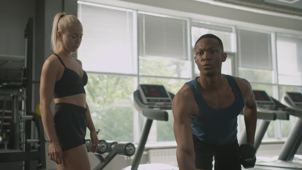 Close-up view of caucasian female monitor and an athletic african american man in the gym.