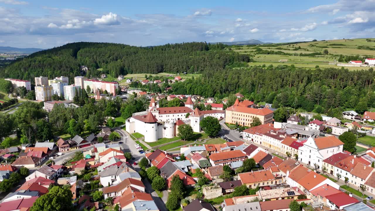 A slow side moving drone shot descending around Kezmarok Castle in Kezmarok, Slovakia, showing its medieval walls, towers and rooftops in calm summer light