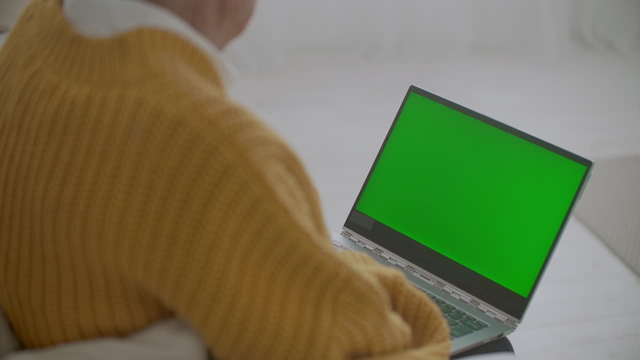mujer madura asintiendo con la cabeza sí mientras mira una computadora de pantalla verde. mujer madura anciana con cabello gris y una videollamada en su computadora portátil. computadora portátil con pantalla verde