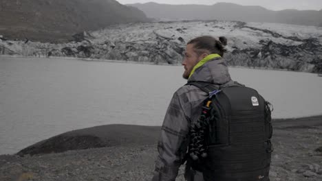 man tourist by glacial lake, iceland mountainscape. slow-motion