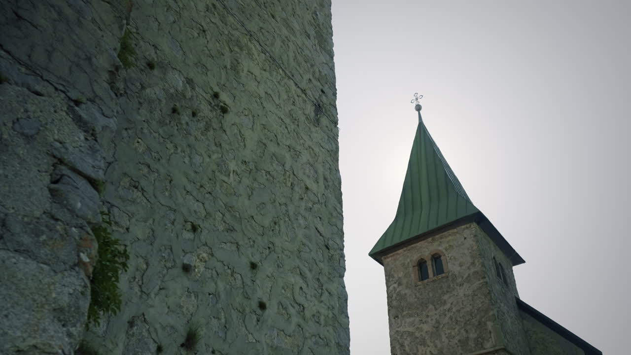 toma recursiva inferior de la antigua torre y la iglesia en la cima de la colina con un hermoso cielo azul y sol detrás de la iglesia en verano, kum eslovenia
