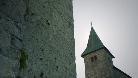 lower recurse shot of old tower and the church on the top of the hill with beautiful blue sky and sun behind the church in summertime, kum slovenia