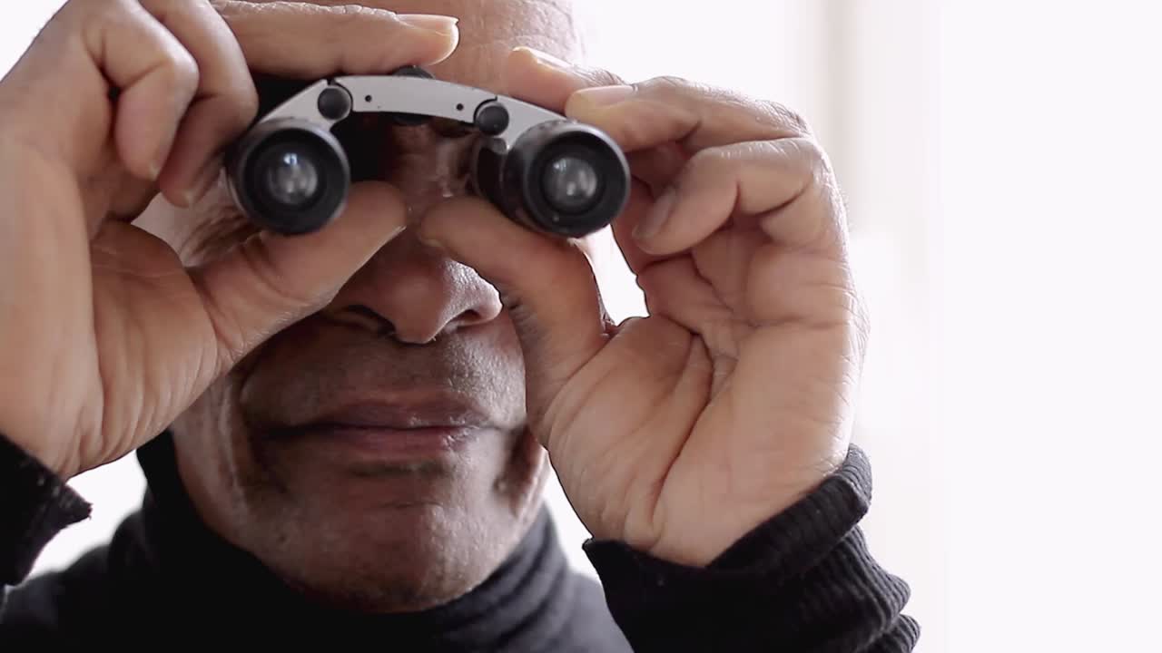 binoculares mirando a través de binoculares con fondo blanco almacen de metraje de video