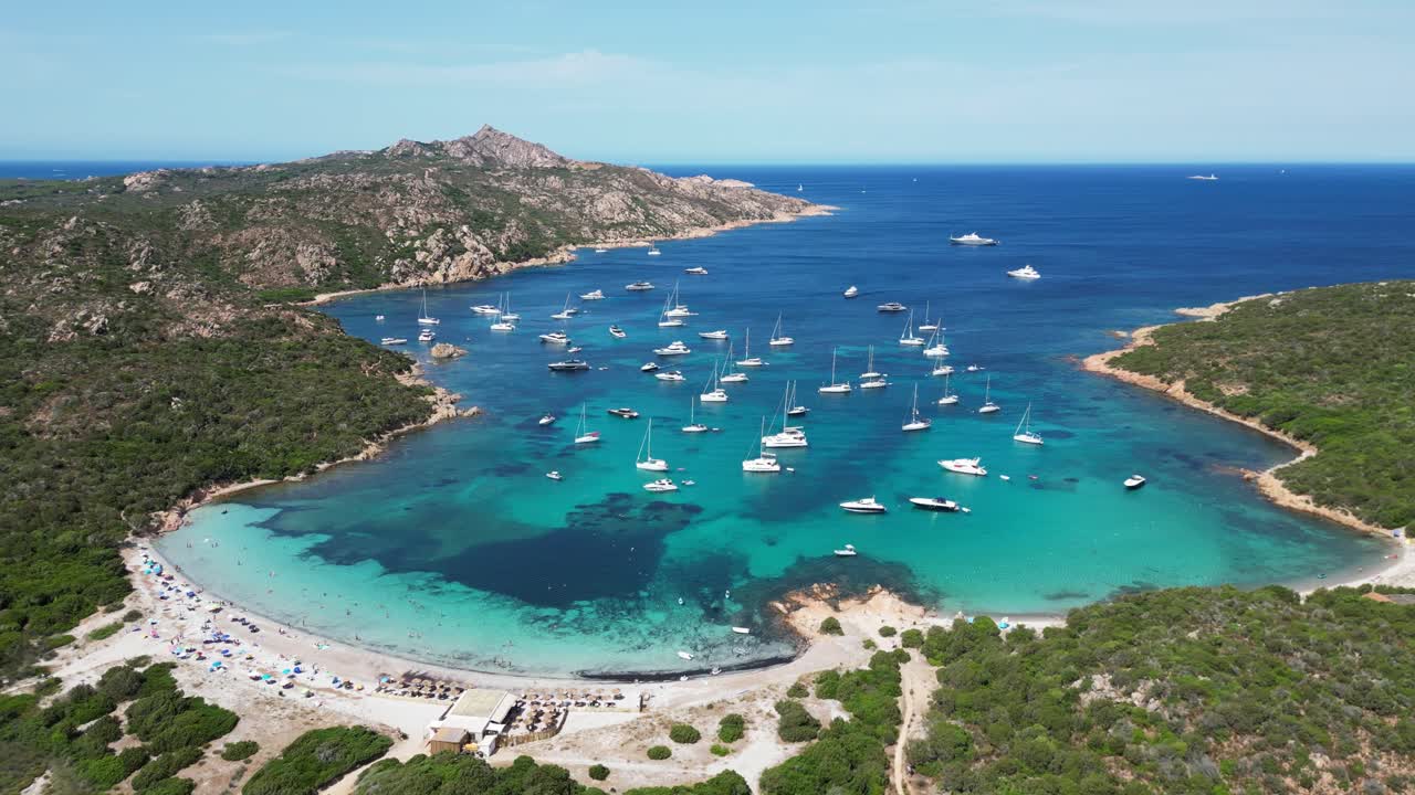 Barcos e iates flutuando em uma enseada azul-turquesa na Ilha La Maddalena, Sardenha - Vista aérea 4K circular