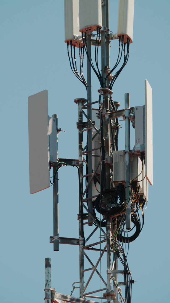 Primo piano di un'antenna di telecomunicazioni montata su una struttura a torre metallica contro un cielo azzurro limpido.