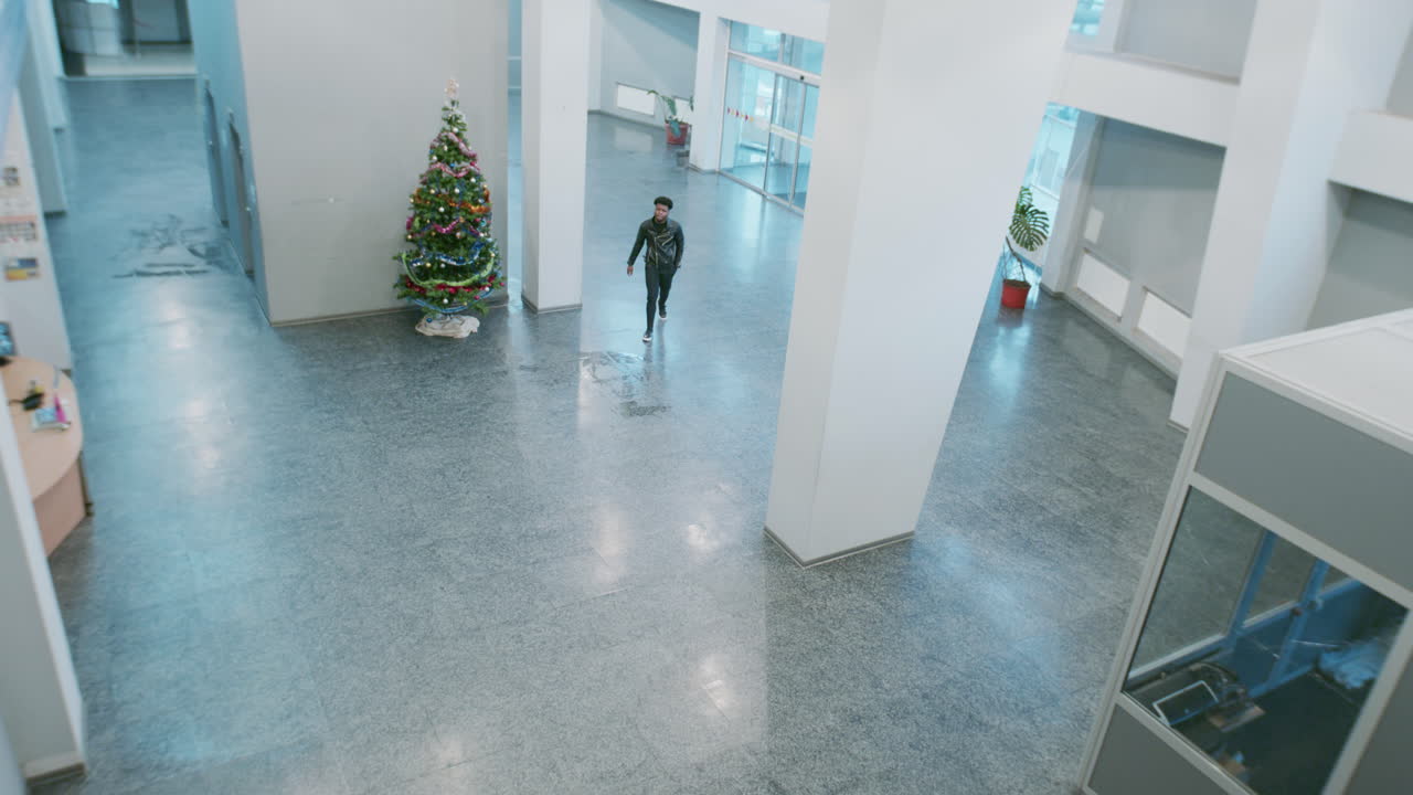 Two people meet and interact in a bright building lobby with a Christmas tree