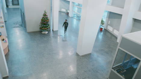 two people meet and interact in a bright building lobby with a christmas tree