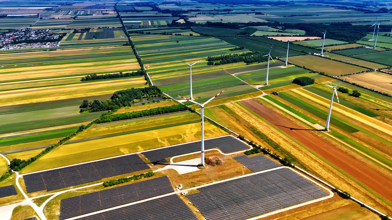 Spectacular scenery of the picturesque countryside with colorful fields. Wind mills and solar panels produce energy in the rural area. Drone footage