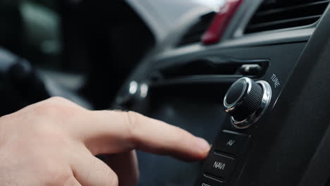 male hand adjusts the tuning of the car radio close-up shot