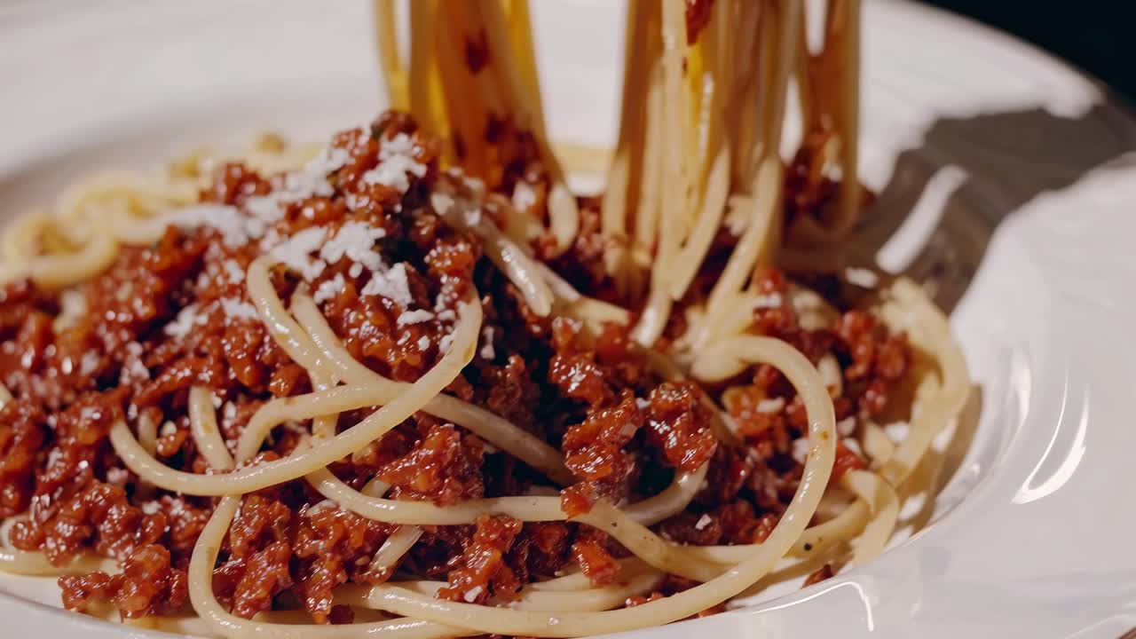 濃厚なミートソースがかかったスパゲッティをローアングルで撮影し、質感やディテールを捉えたクローズアップ動画