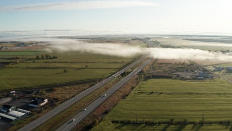 Lückenhaft-Dichter-Morgennebel-Hängt-über-Der-Interstate-Highway,-Während-Der-Verkehr-Durch-Flache,-Grüne-Farmfelder-Führt