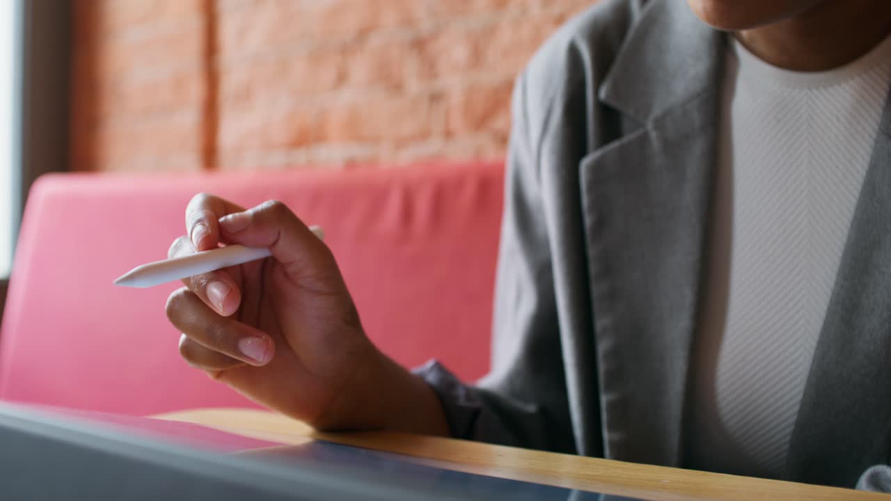 Woman using stylus on a digital tablet in a cafe