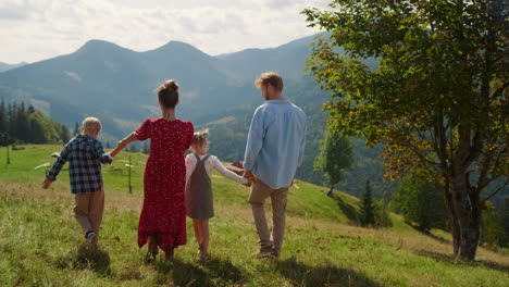 Back-view-family-walking-on-mountains-hill-sunny-day.-Summer-vacation-together.