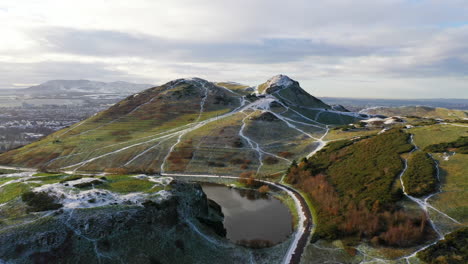 Aerial-shot-of-Snow-on-Arthurs-seat-in-Edinburgh,-flying-over-Dunsapie-Loch