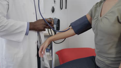 diverse male doctor examining female patient, measuring blood pressure, slow motion