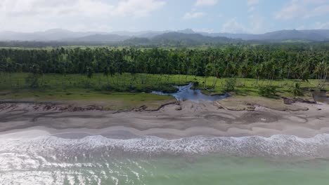 ujęcie drona transportowego przedstawiające dotarcie do wody oceanu na piaszczystej plaży i tropikalnej playa bahia esmeralda, miches