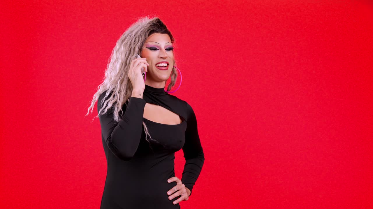 Drag queen espressiva che ride al telefono su sfondo rosso
