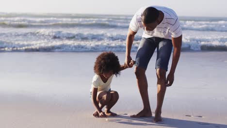 Padre-E-Hija-Afroamericanos-Recogiendo-Conchas-De-La-Arena-Juntos-En-La-Playa