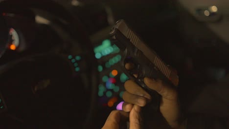 close up of a black man inserting a loaded clip into his handgun and cocking it to load a bullet in the chamber