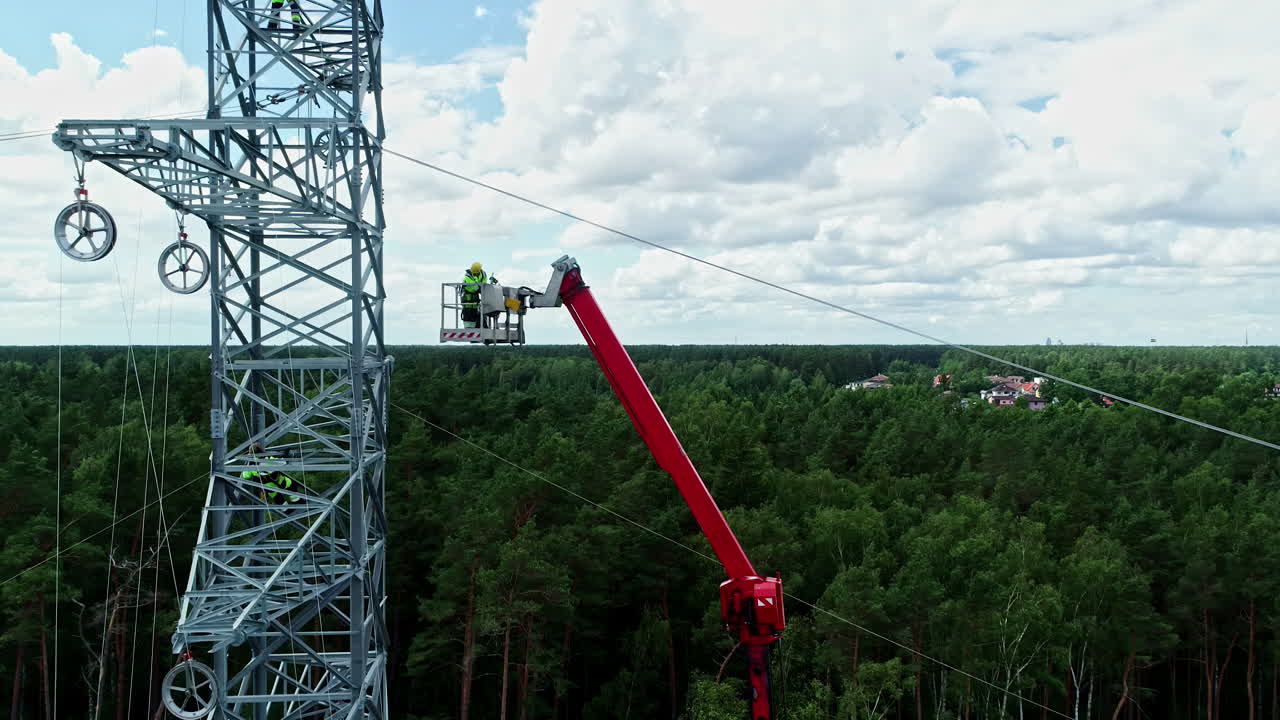 disparo de empleados en uniforme por una grúa, instalando cables en un poste eléctrico por encima en un día nublado