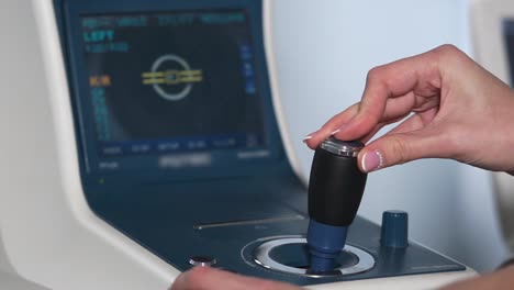 mujer ajustando la perilla de control en la máquina de oftalmología