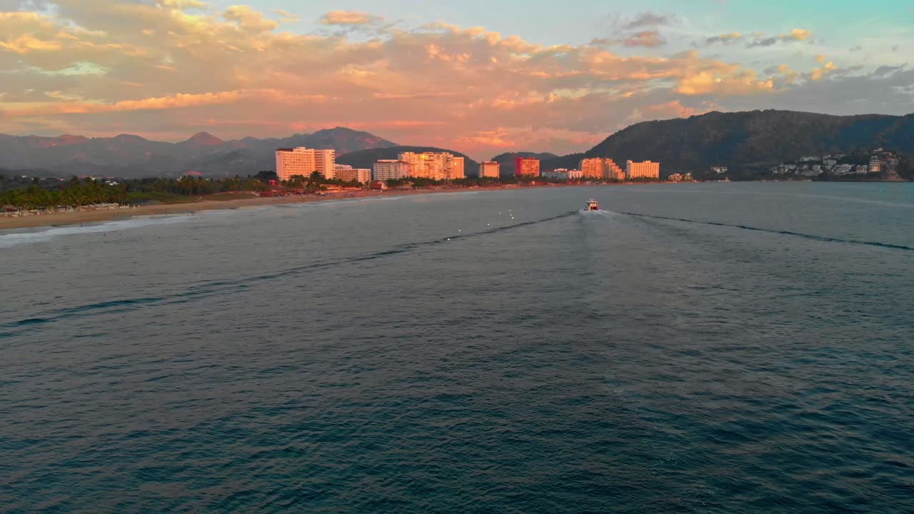 DRONE : FOLLOWING SHOT OF A BOAT AT SUNSET IN IXTAPA ZIHUATANEJO