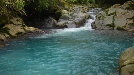 river with crystal clear water running between rocks in the rainforest of costa rica with azure blue water