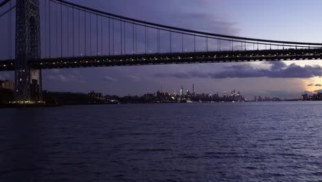 sailing-through-the-East-River-in-New-York-City-at-eventide,-approaching-the-Manhattan-Bridge