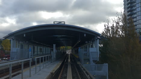 train moving through the railways in vancouver, canada with green trees and buildings - steady shot