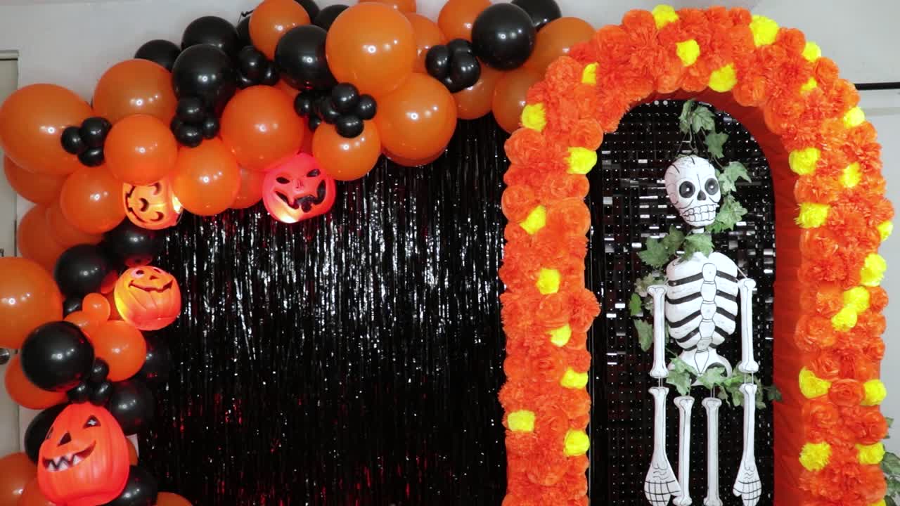Halloween balloons, pumpkins and skeleton on cempasuchil garland.