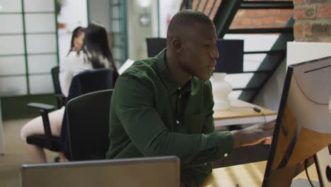 Happy-african-american-businessman-using-laptop-at-office