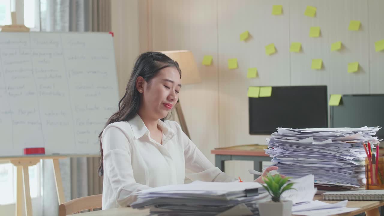 Tired Asian Woman Yawning While Working Hard With Documents At The Office