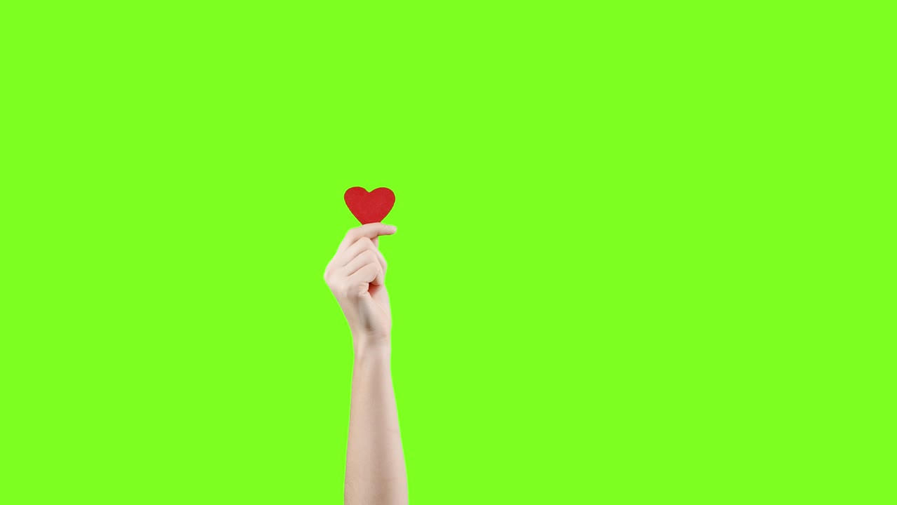 blogger mujer sostiene en la mano un pequeño corazón rojo en la pantalla verde. como en la red social. día de san valentín, día internacional de la mujer, amor