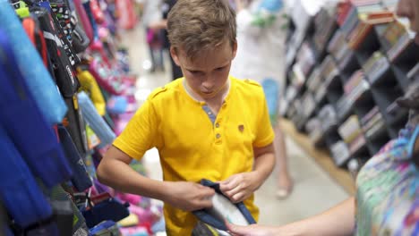 boy choosing school stationery. young boy choosing school supplies in stationery shop