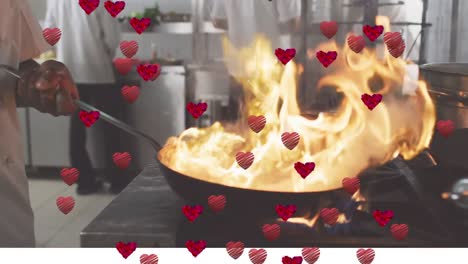 animation of heart icons over african american male chef cooking with frying pan