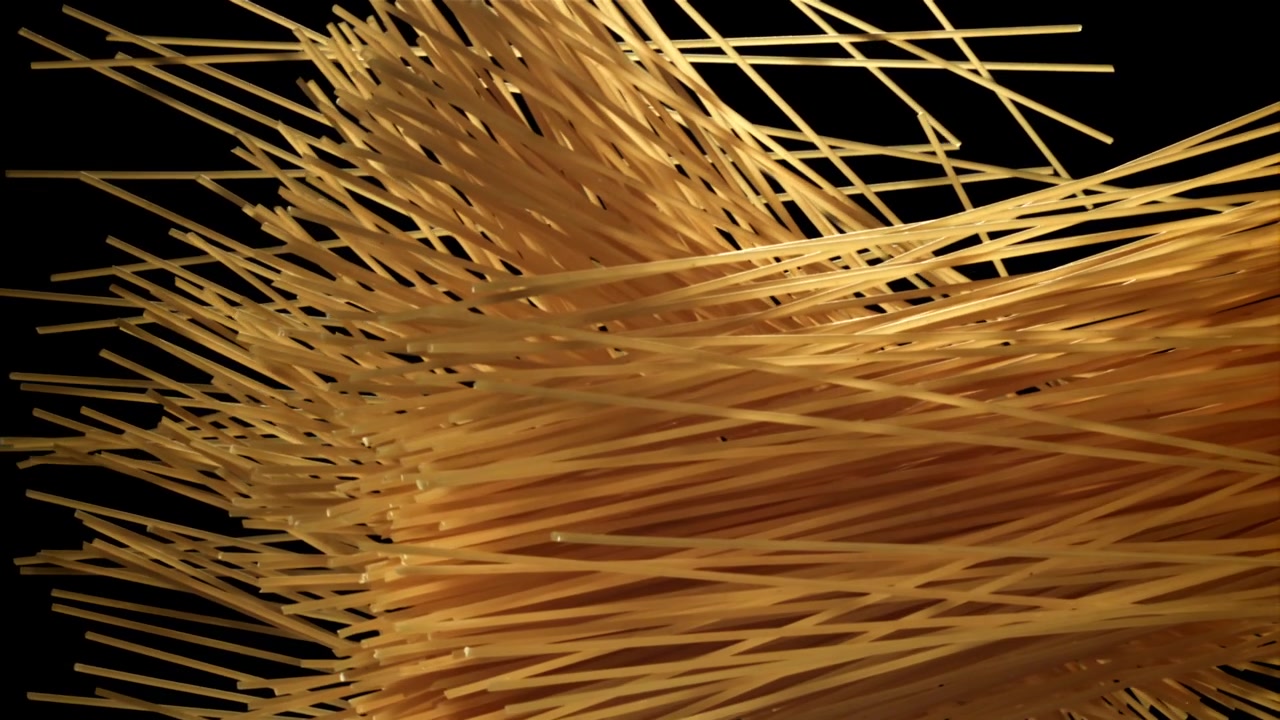Primo piano di spaghetti secchi che cadono su sfondo nero