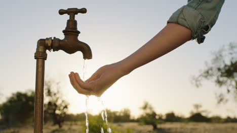 Frauenhände-Fangen-Wasser-Unter-Leitungswasser-Auf-Durstiger-Bauer-Trinkt-Süßwasser,-Das-Bei-Sonnenuntergang-Aus-Dem-Wasserhahn-Fließt,-Spart-Wasserkonzept