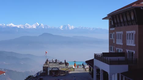 kathmandu, nepal - december 12, 2021: people swimming in a swimming pool at a resort with the himalayan mountains in the background