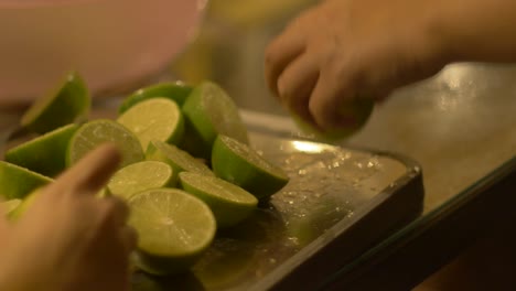 Limones-Verdes-Recién-Recogidos-Que-Se-Cortan-Por-La-Mitad-En-Una-Tabla-De-Cortar-De-Madera,-Filmados-Como-Un-Primer-Plano