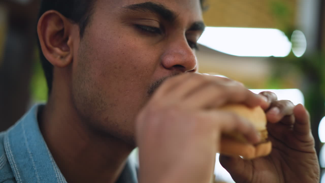Homem com Cabelo Volumoso Limpando a Boca com Guardanapo Após Comer, Close-up Mostrando Expressão e Lábios Sujos, Ambiente Interno Casual com Desfoque Suave no Fundo, Foco no Gesto de Limpeza e Satisfação
