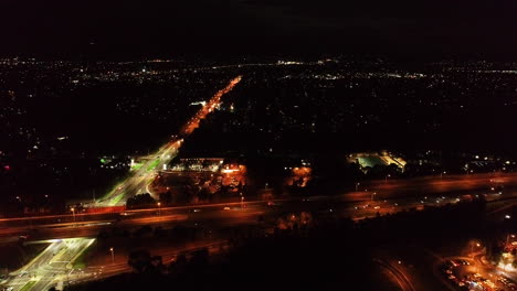 Tiro-De-Seguimiento-Lento-De-Automóviles-Que-Se-Mueven-A-Lo-Largo-De-La-Conexión-De-La-Autopista-Debajo-Por-La-Noche