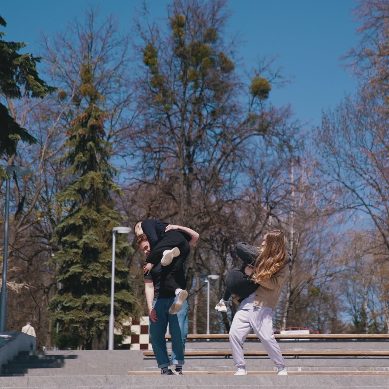 Positive friends having fun in the park in autumn. Teenage boys and a girl enjoy the time together outdoors. Happy youth lifestyle